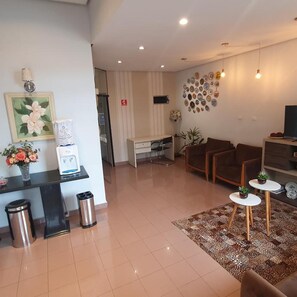 A modern living room with a sofa, coffee table, and decorative plates on the wall. - Hotel Magnolia (Sao Joao da Boa Vista)