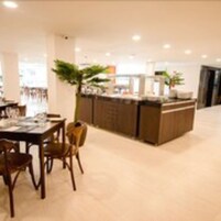 A modern restaurant with a central island, seating area, and a view of the dining area.