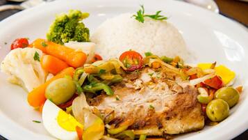 Un plato con pollo a la parrilla, arroz y una variedad de verduras, incluyendo zanahorias, brócoli y pimientos.