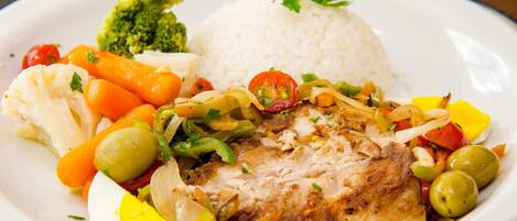 A plate with grilled chicken, rice, and a variety of vegetables including carrots, broccoli, and bell peppers.