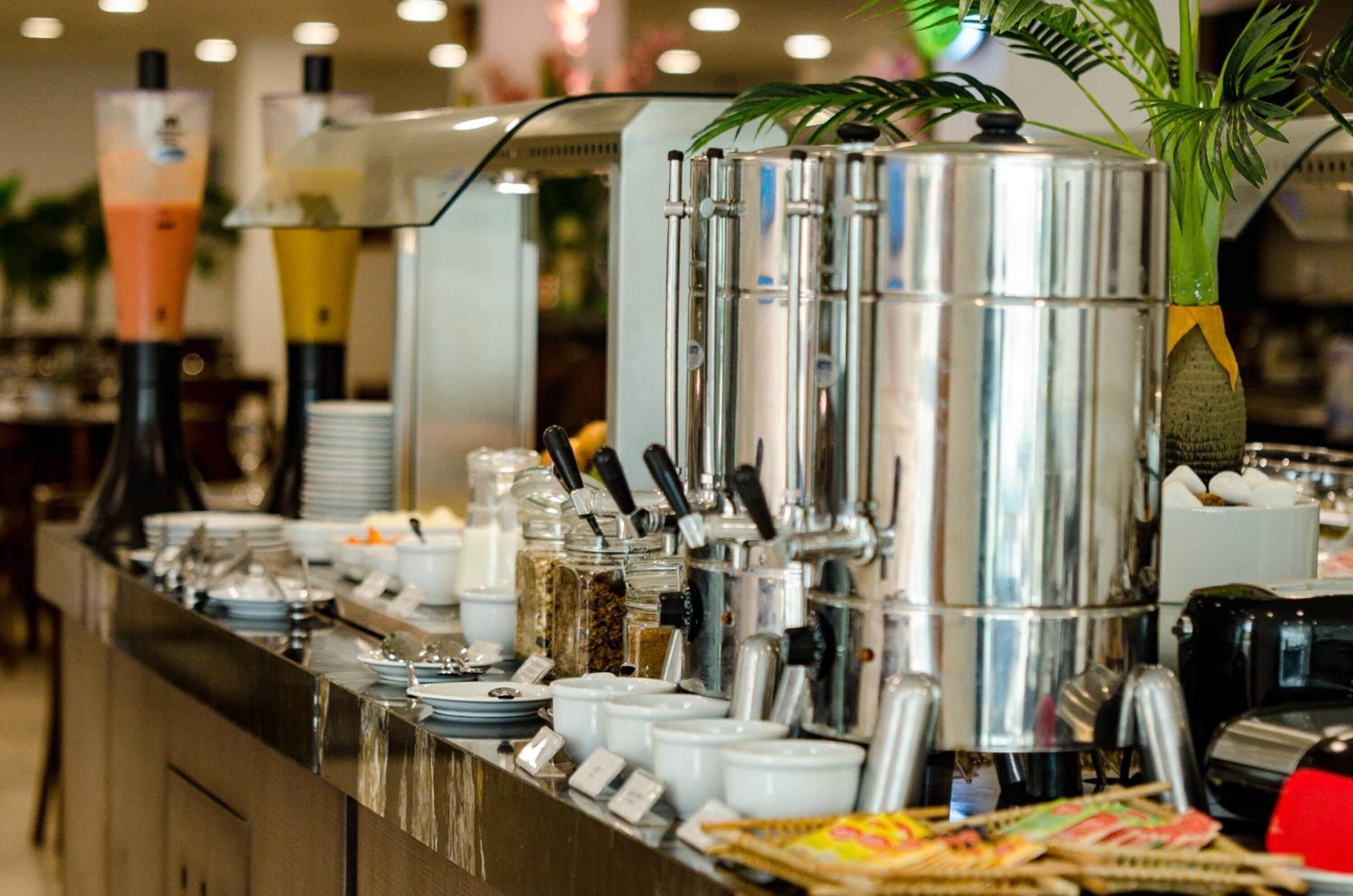 Montaje de bufé con varios dispensadores de bebidas y una variedad de recipientes para alimentos.