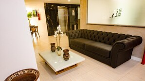 A modern lobby with a dark leather sofa, a white coffee table with decorative vases, and a patterned floor. - Bristol Umarizal Belem (Belém)
