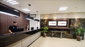 A reception area with a reception desk, two potted plants, and a wall-mounted sign displaying the hotel's name. - Bristol Umarizal Belem (Belém)