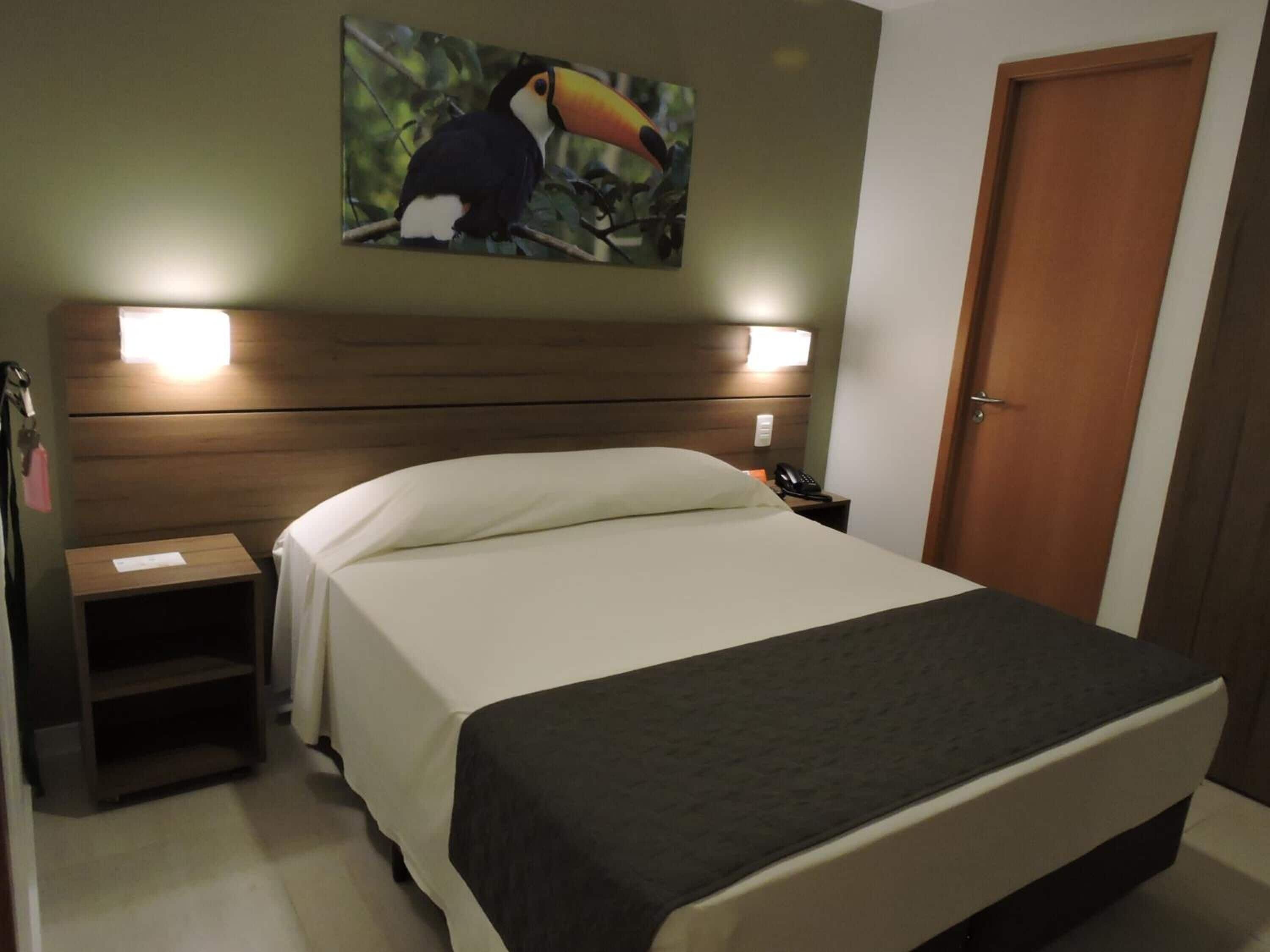 Una habitación de hotel con una cama, una mesita de noche, un teléfono y una puerta.