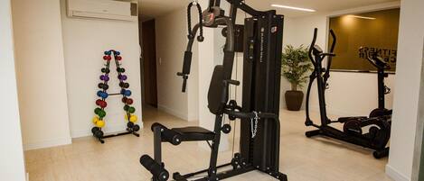 A home gym with a squat rack, bench press, and various weights.