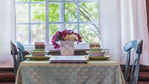 A table with a vase of flowers, a notebook, and two small boxes labeled "STASH" on a tablecloth. - Log Cabin Motel (Pinedale)