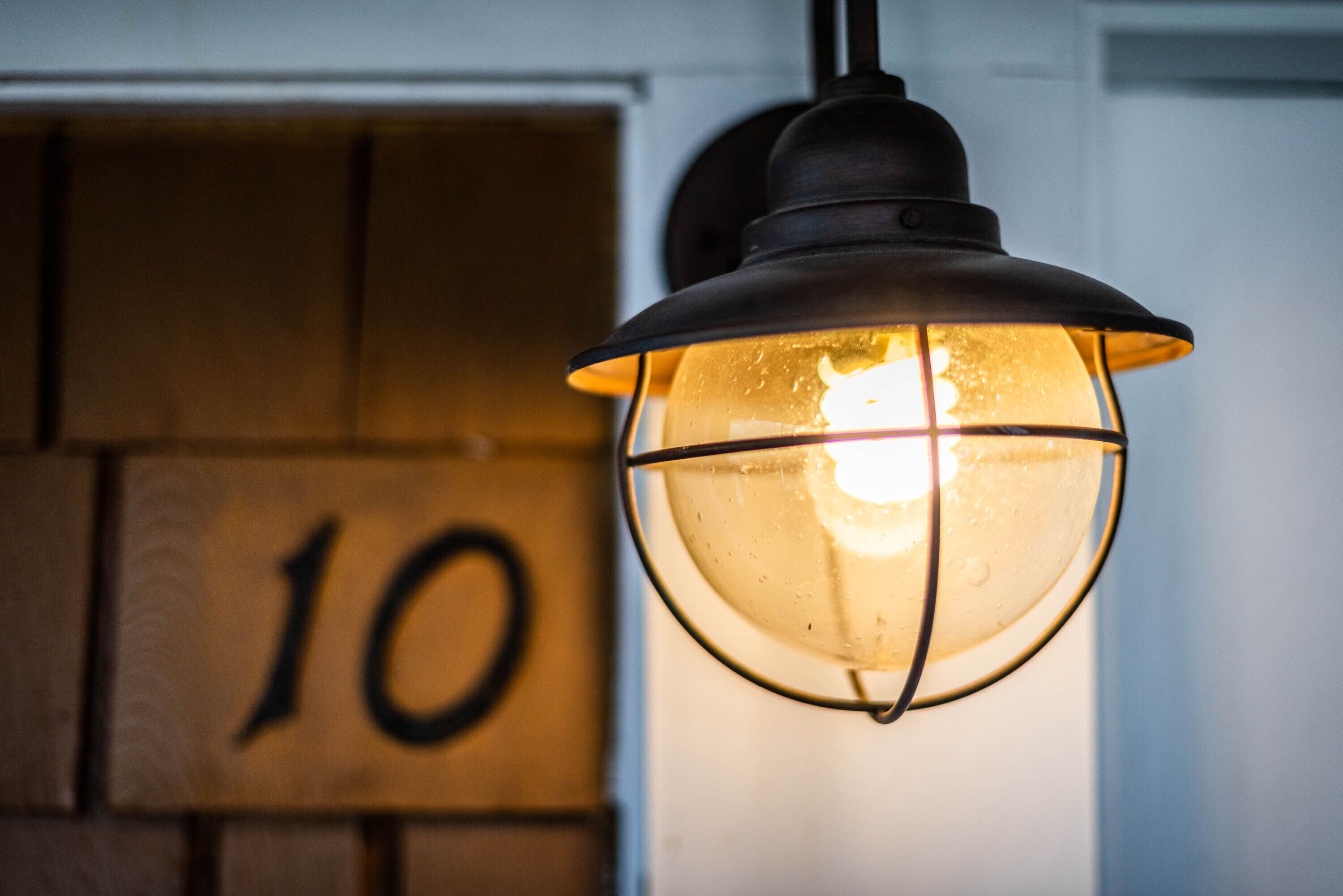 A hanging light fixture with a glass enclosure and a metal frame, mounted on a wall with a visible number '10'.