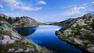 A serene lake surrounded by rocky terrain and sparse vegetation.
