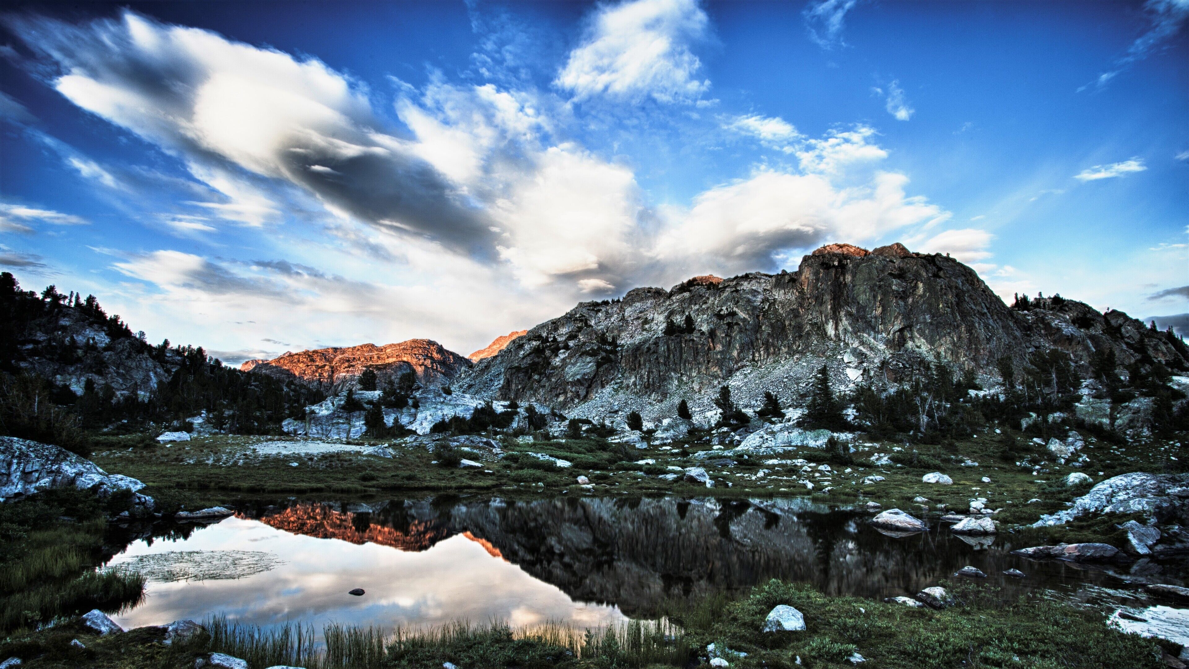 A mountainous landscape with a clear sky, a reflective lake, and snow-covered terrain.