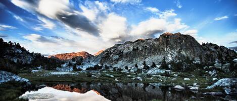 A mountainous landscape with a clear sky, a reflective lake, and snow-covered terrain.