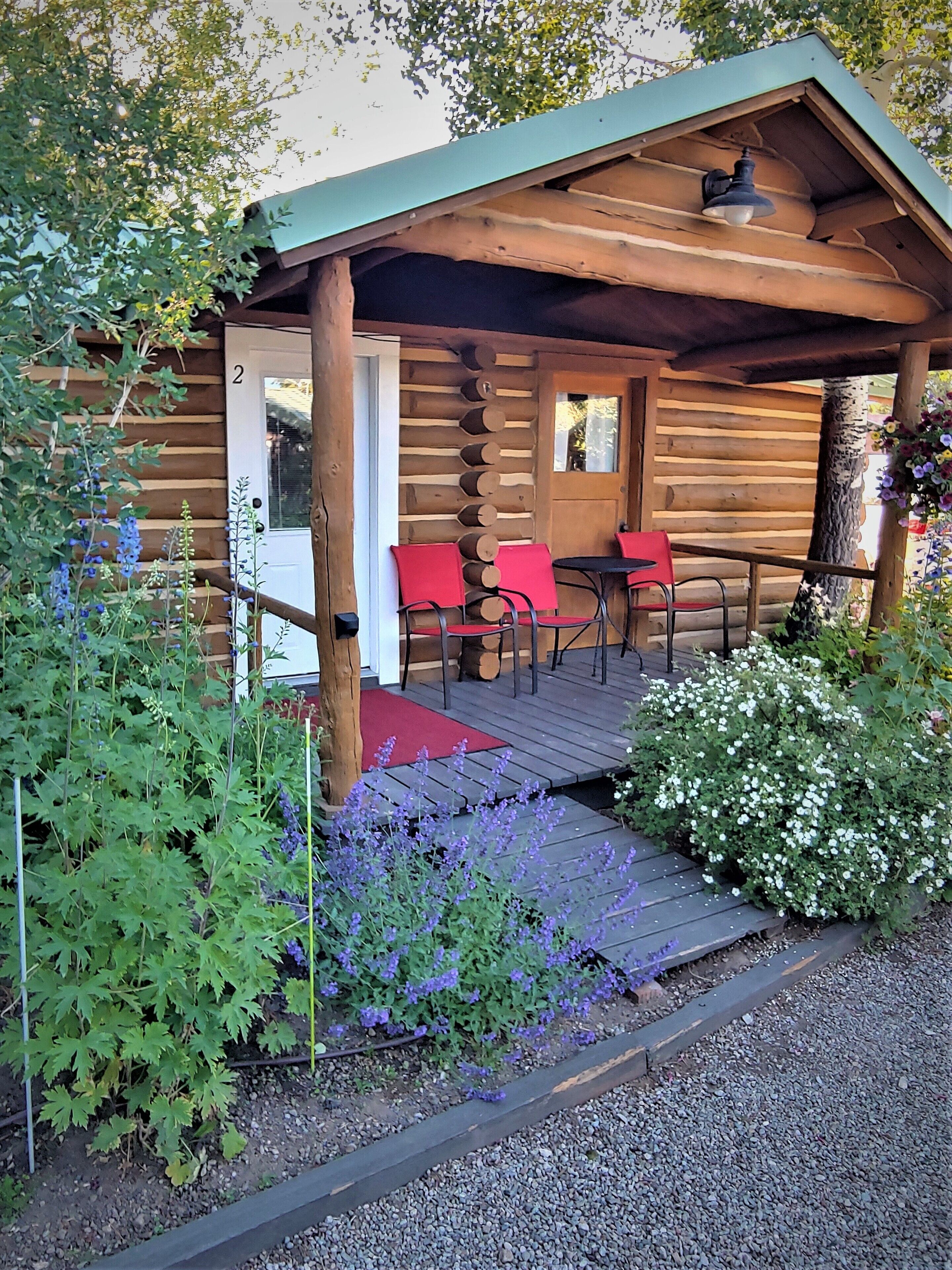A log cabin with a porch, two red chairs, and a small table.