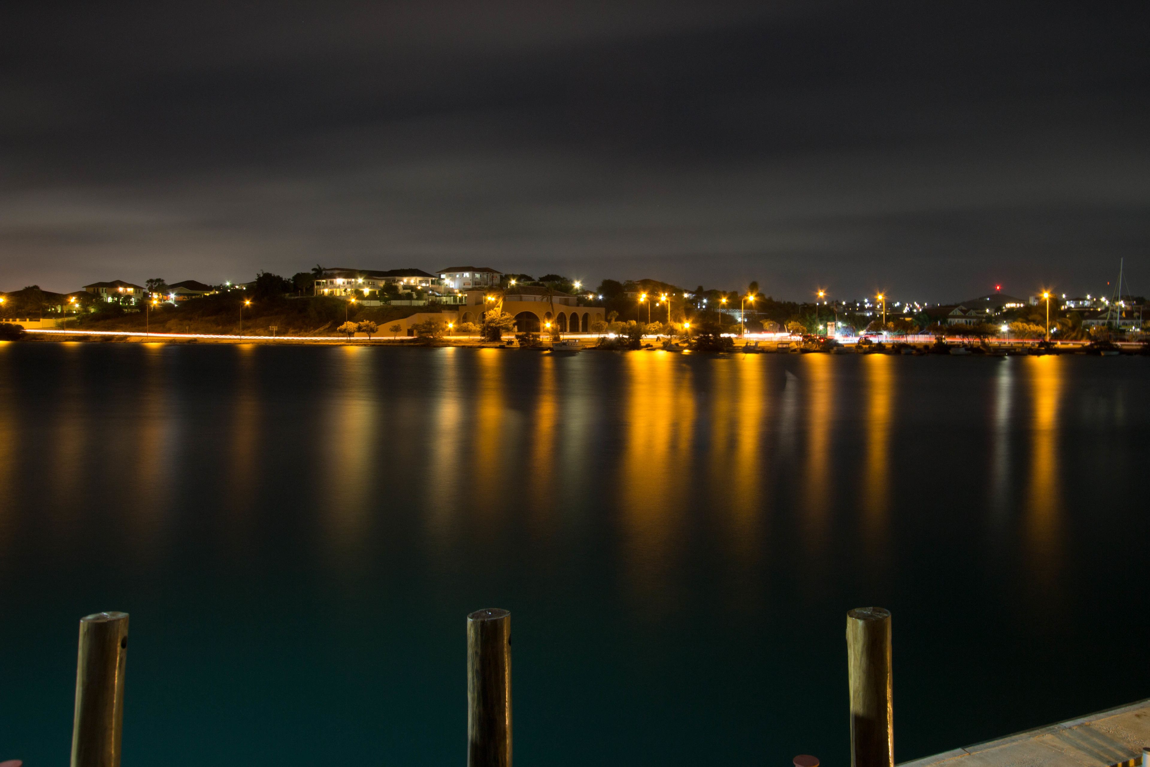Vista nocturna del paseo marítimo con edificios iluminados y agua tranquila.