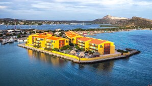 A waterfront hotel with multiple yellow buildings, a dock, and boats in the background. - Palapa Beach Resort (Jan Thiel)