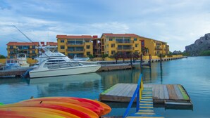 A marina with boats, colorful kayaks, and a building with balconies. - Palapa Beach Resort (Jan Thiel)