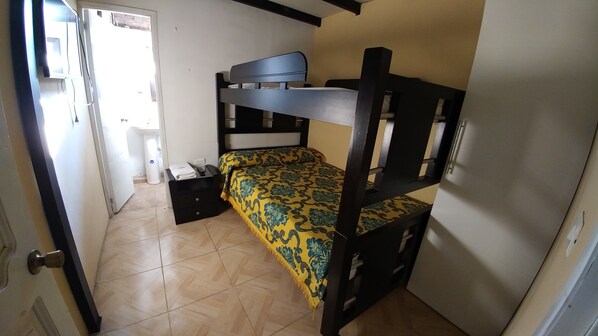 A small, compact room with a bunk bed, a bedside table, and a chair.