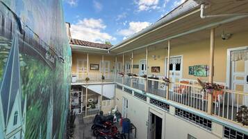 Un edificio de varios pisos con balcones, un espacio al aire libre cubierto y motocicletas estacionadas.