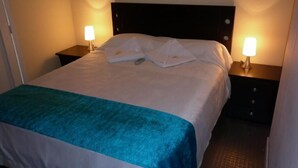 A neatly made bed with a teal throw blanket, two bedside lamps, and a dark headboard. - Hotel Santa Juana (Santa Rosa de Cabal)