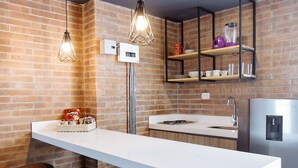 A modern kitchen with a central island, pendant lighting, and a brick wall. - Soy Local Provenza (Medellín)