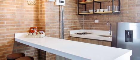 Une cuisine moderne avec un îlot central, des luminaires suspendus et un mur en briques.