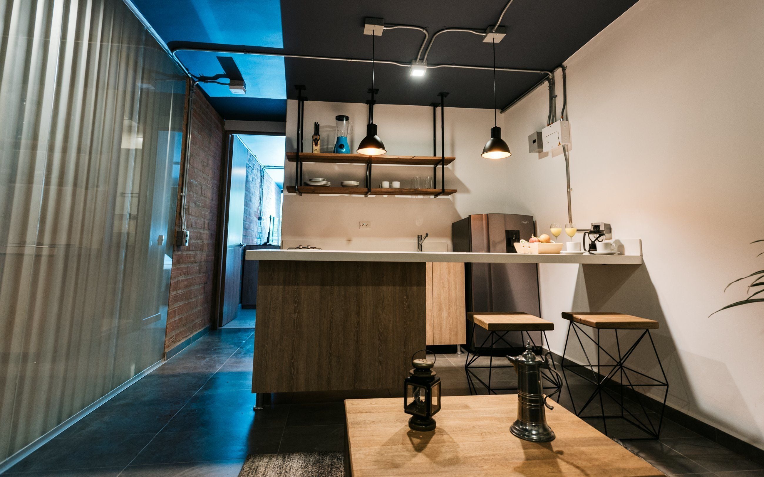 Een moderne keuken met een centraal eiland, hanglampen en een uitzicht op de aangrenzende kamer.
