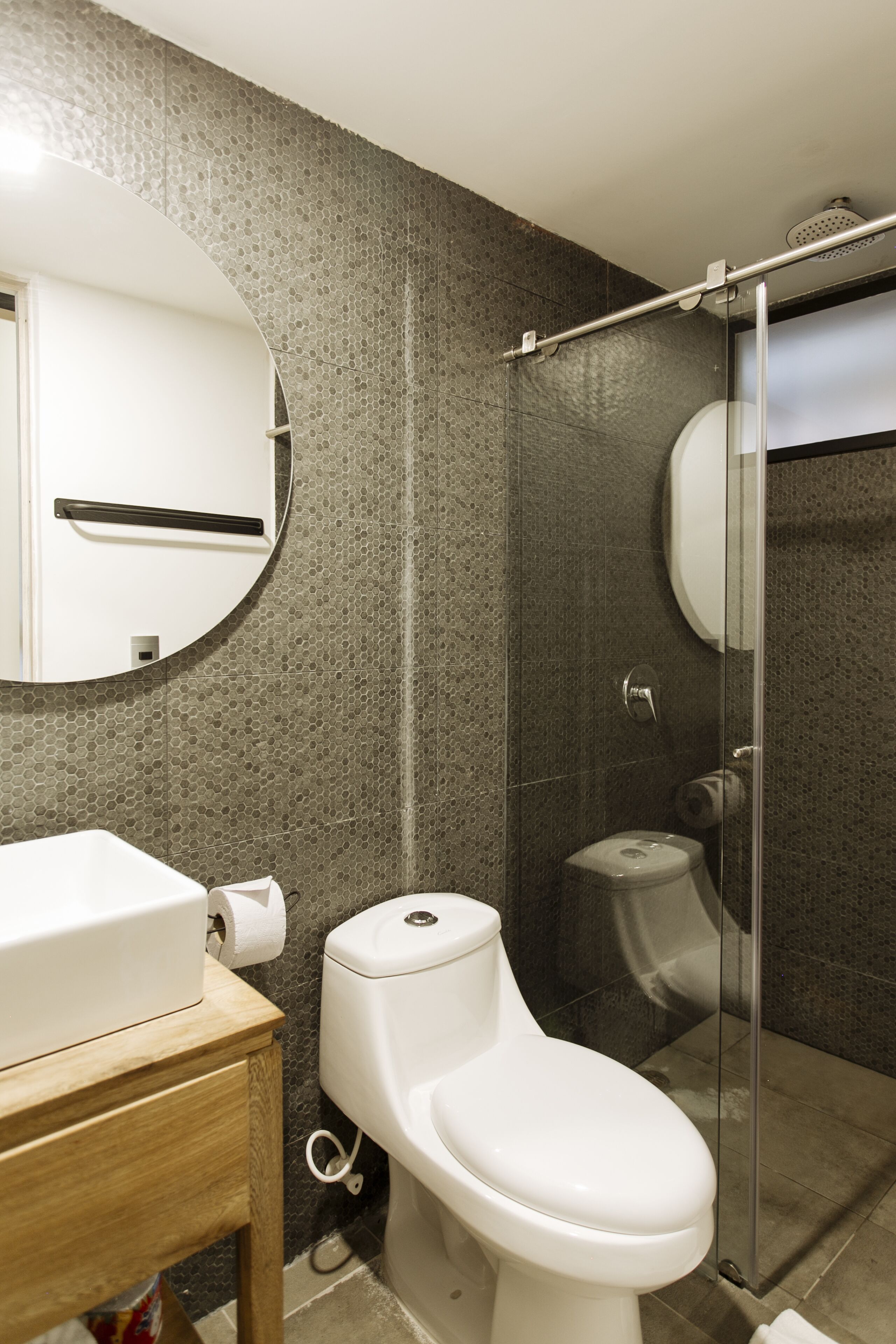 Un baño moderno con inodoro, lavamanos y zona de ducha.