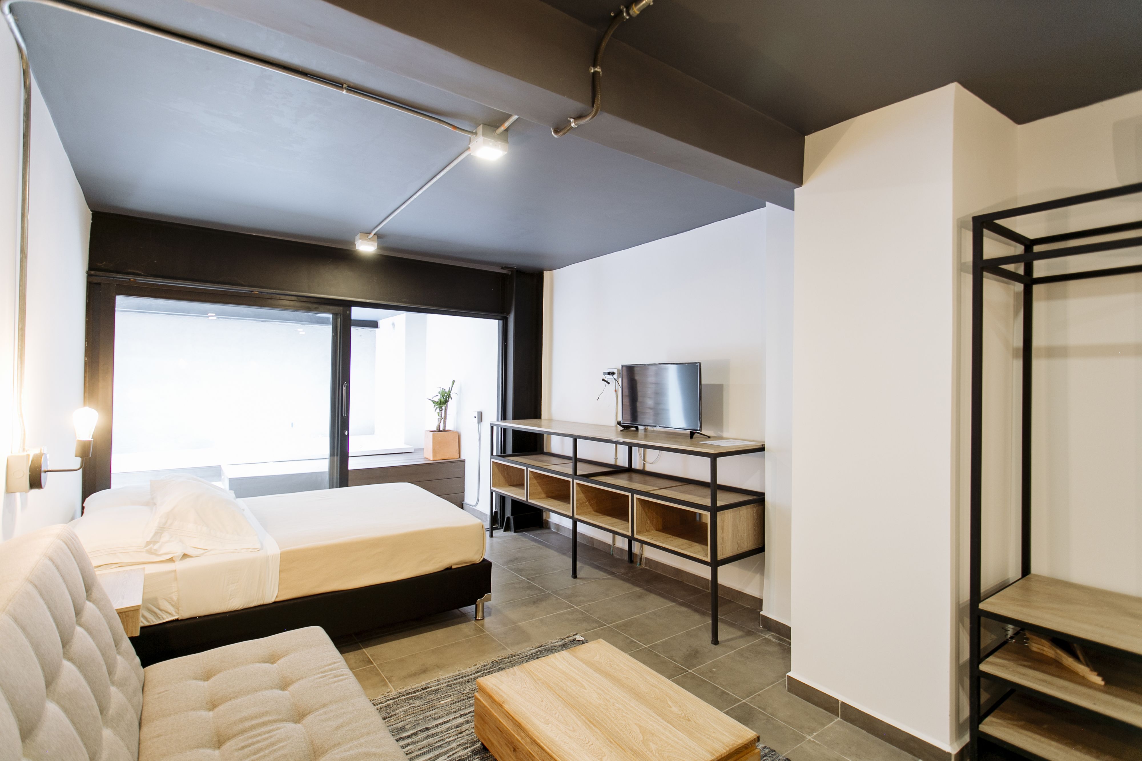 Une chambre à coucher moderne avec un lit, un canapé, un bureau et un téléviseur.