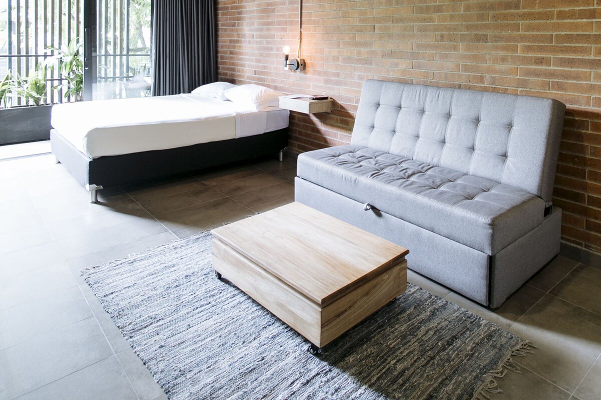 A modern room with a bed, sofa, and a small wooden table.