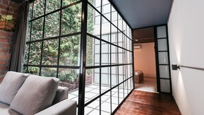 A modern interior with a large window, a wooden floor, and a grey sofa. - Soy Local Provenza (Medellín)