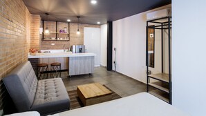 A modern kitchen with a bar area, a seating area with a sofa, and a wooden coffee table. - Soy Local Provenza (Medellín)