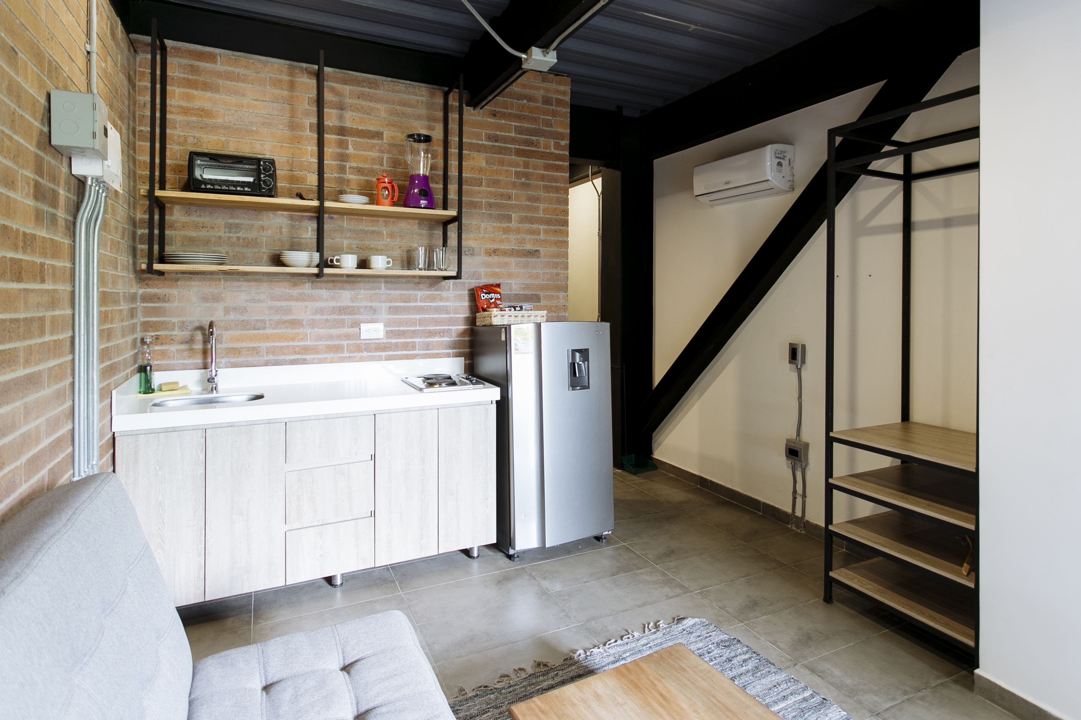 Una cocina compacta con horno integrado, refrigerador y cafetera sobre la encimera.