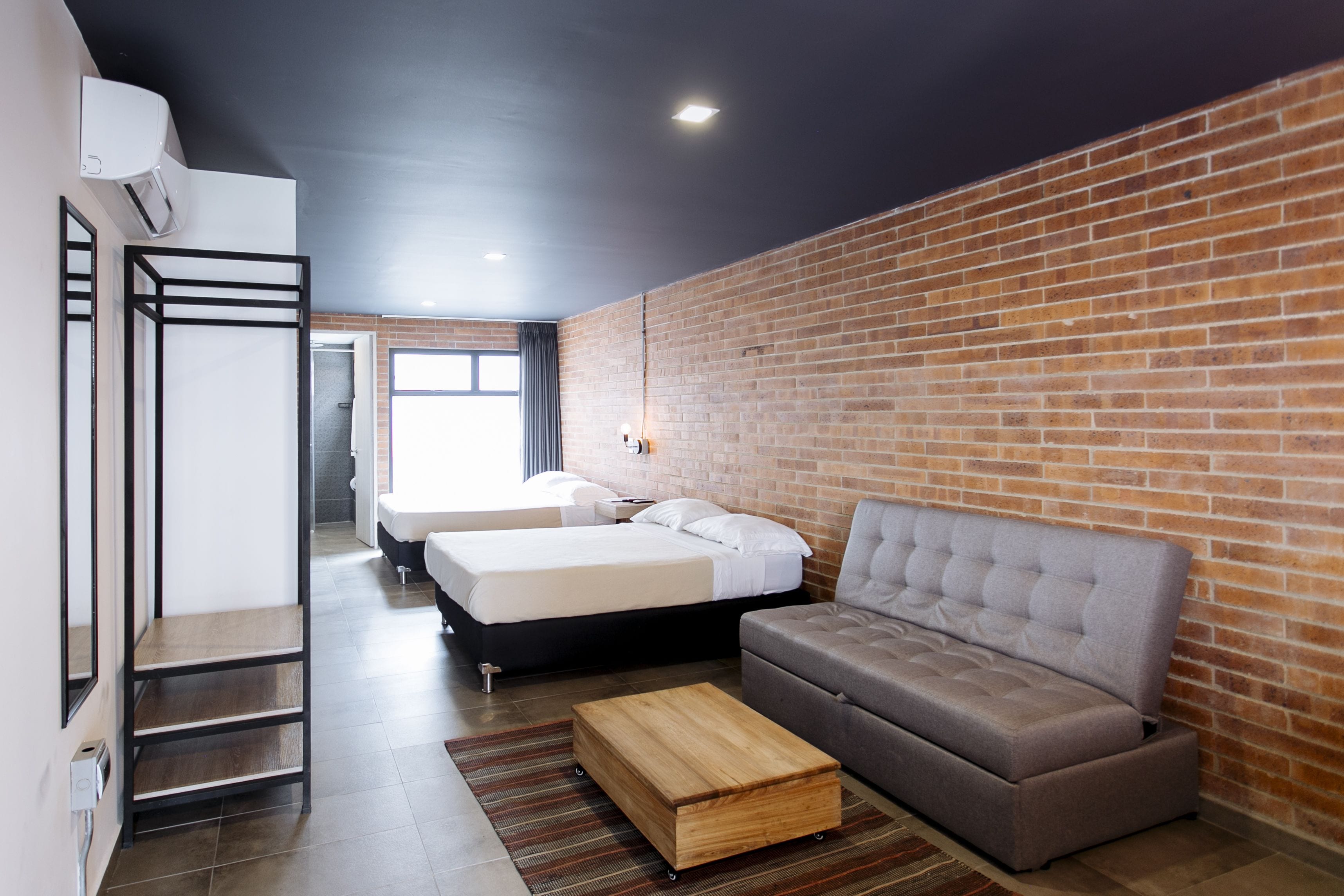 Ein modernes Zimmer mit Backsteinwand, einem Bett, einer Couch und einem Holztisch.