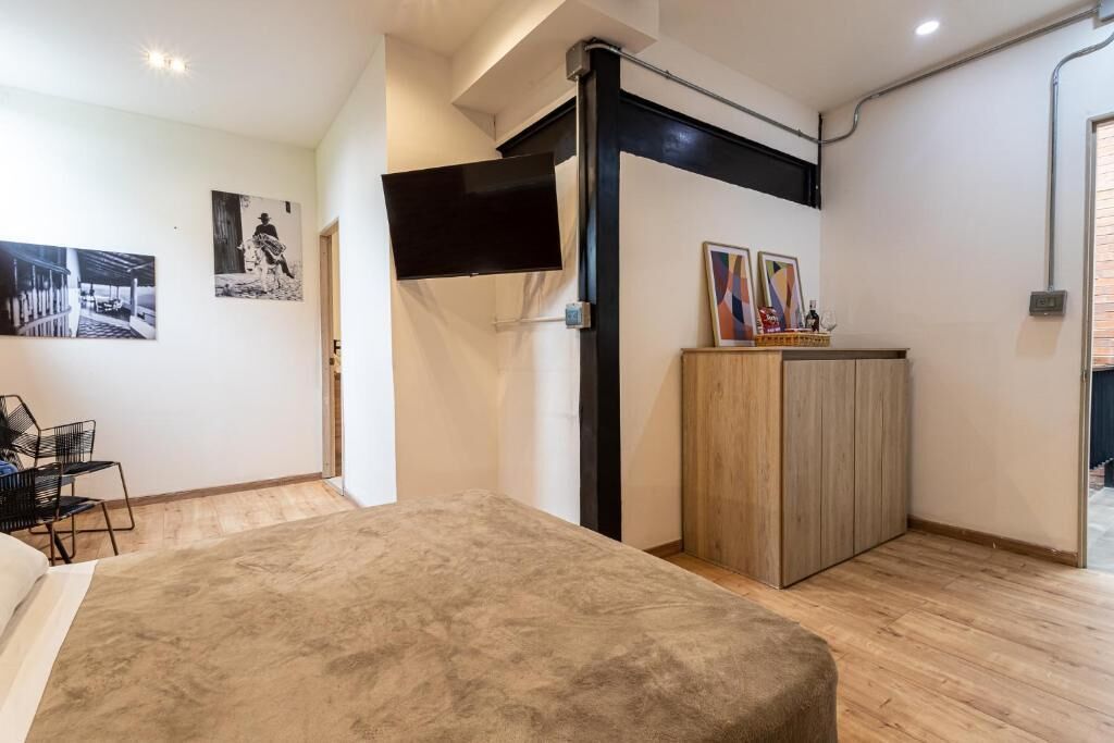 Ein Schlafzimmer mit Bett, Schreibtisch und Stuhl. An den Wänden befinden sich Bilder.