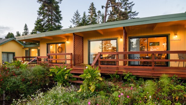 A two-story lodge with a wooden deck and a garden in front. - Inn at Buckhorn Cove (Little River)