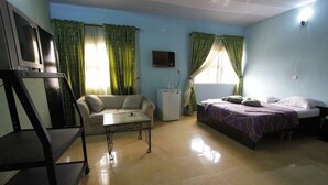 A room with a bed, a sofa, a small table, a TV, and a refrigerator. - Sylva Link Hotel (Lagos)