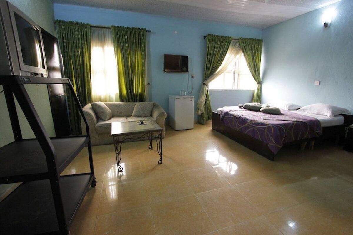 A room with a bed, a sofa, a small table, a TV, and a refrigerator.