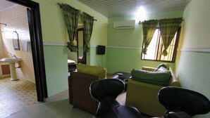 A room with a bed, two chairs, a small table, a mirror, and a window with curtains. - Sylva Link Hotel (Lagos)