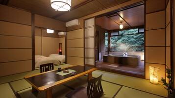 Una habitación japonesa tradicional con suelo de tatami, una mesa baja y un fusuma que da a un balcón con hidromasaje.