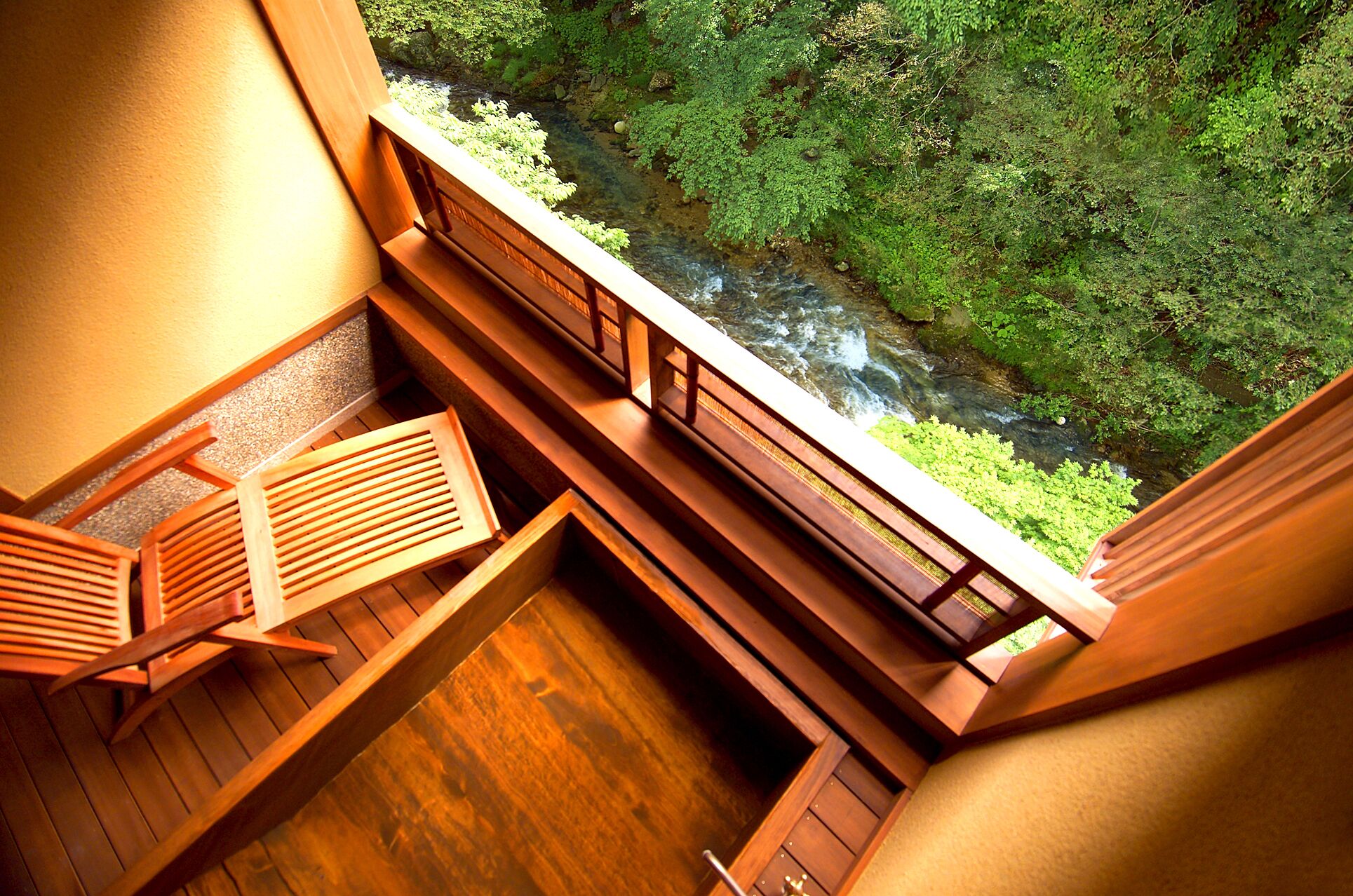 A wooden deck with a view of a river and greenery.