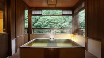 Relax in a serene space with a large hot tub and views of lush greenery.