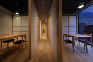 A narrow hallway with wooden flooring and tables on either side.