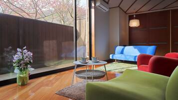 A modern living room with a large window, a blue sofa, a red armchair, and a green sofa.
