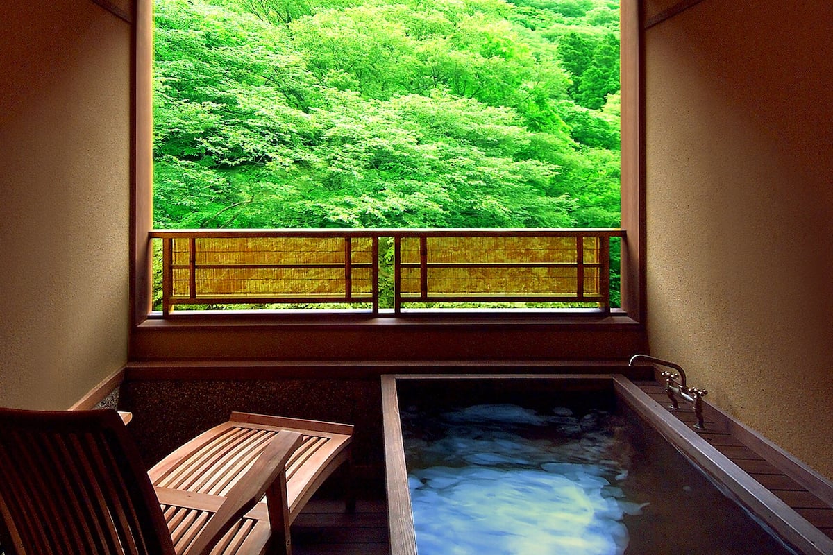 A traditional Japanese onsen with a wooden bench and a view of lush greenery.