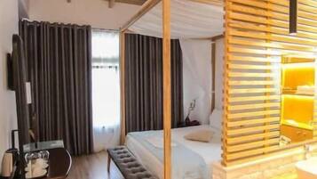 Une chambre dotée d’un lit à baldaquin, d’un bureau avec une chaise, d’une télévision et d’une fenêtre avec des rideaux.
