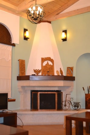 A room with a fireplace, a chandelier, and wall-mounted sconces. - Hotel Vila Sharm (Gjirokaster)
