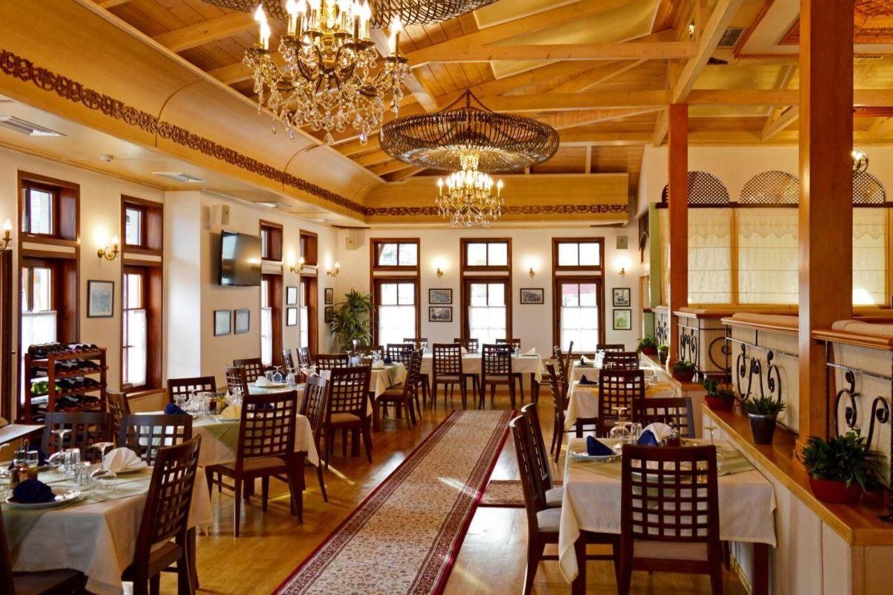 Un restaurant avec des poutres en bois, des lustres et une longue table à manger entourée de chaises.