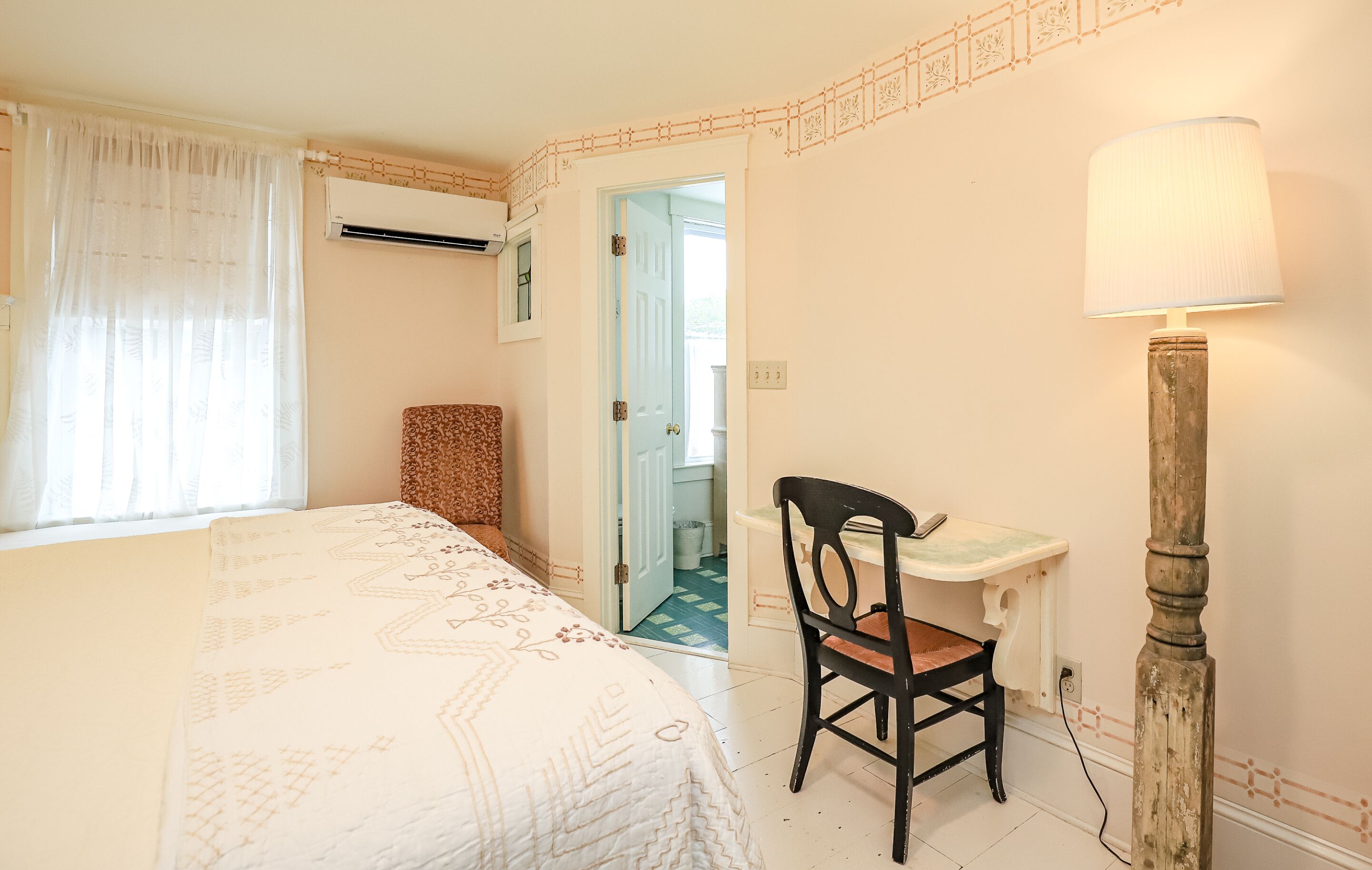Un dormitorio con una cama, un escritorio, una silla y una lámpara.
