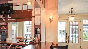 Uma área de bar com balcão de madeira, banquetas e luminárias pendentes.