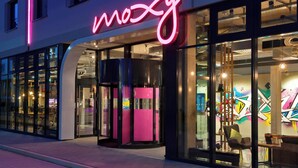 A modern building with a neon sign reading "moxy" and large glass windows. - MOXY Stuttgart Airport/Messe (Leinfelden-Echterdingen)