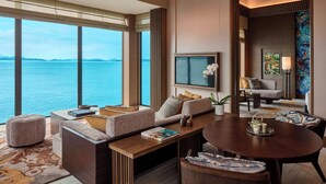 A modern living room with a large window overlooking the sea, a flat-screen TV, and a cozy seating area. - The Ritz-Carlton, Langkawi (Langkawi)
