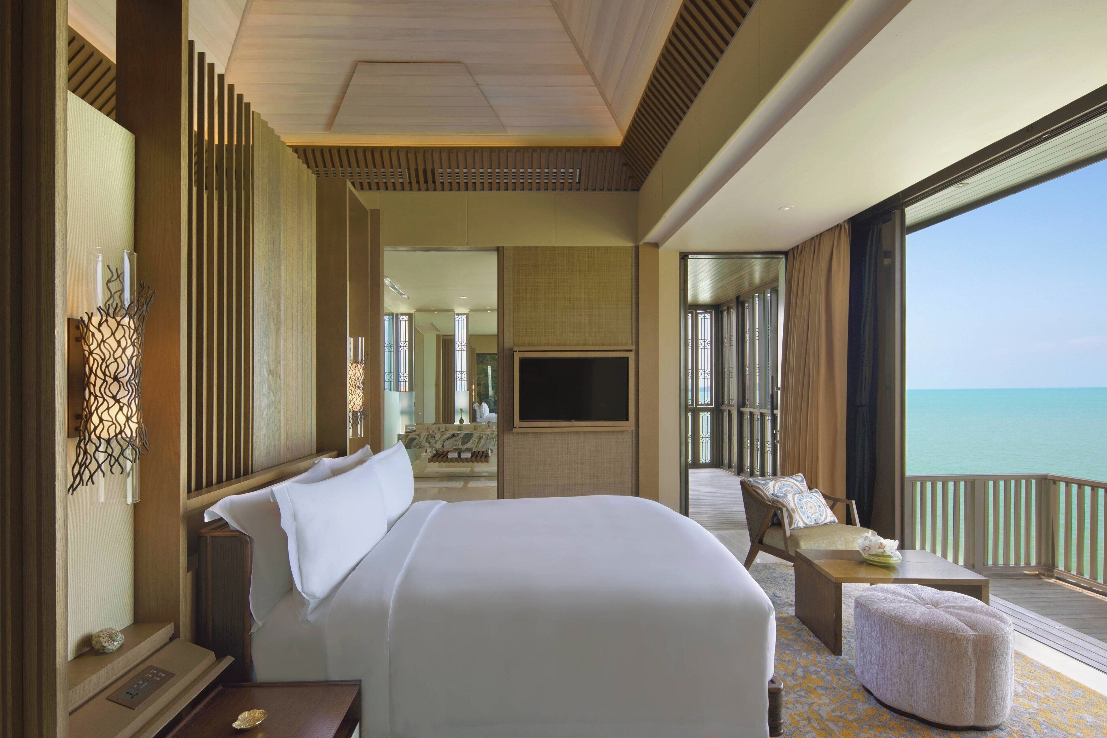 Habitación de hotel con una cama grande, televisión, balcón con vista al mar y una zona de estar con vista al océano.